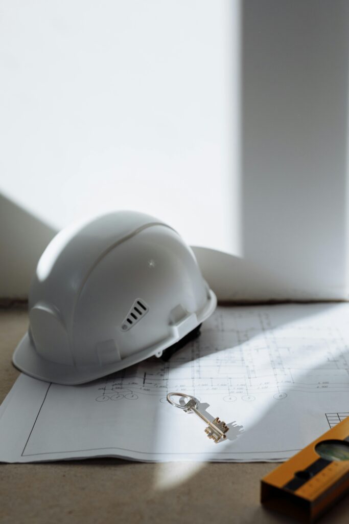 Close-up of a safety helmet and key on a blueprint, symbolizing construction and planning.